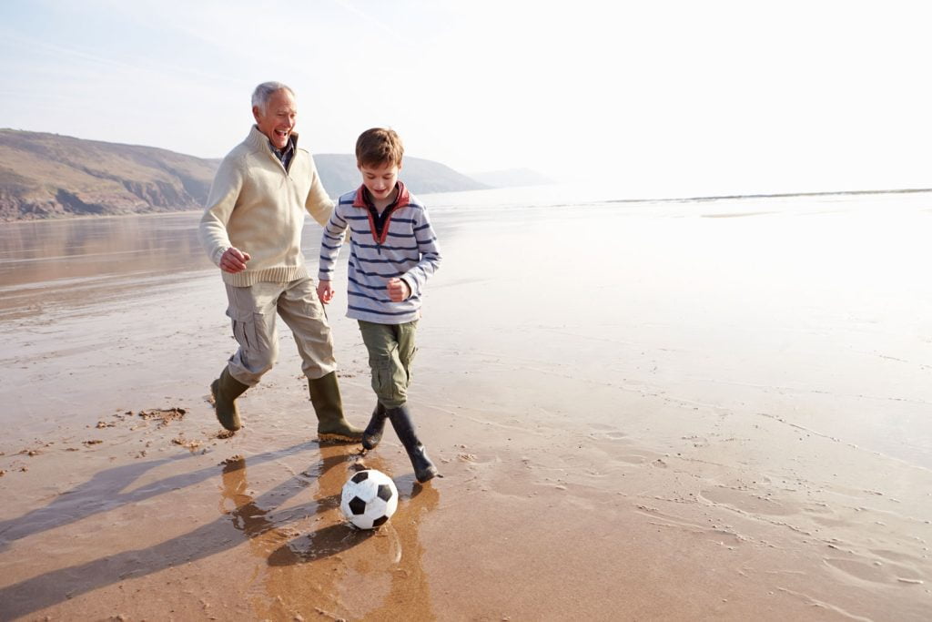 grandson playing football on beach - savings and investments page